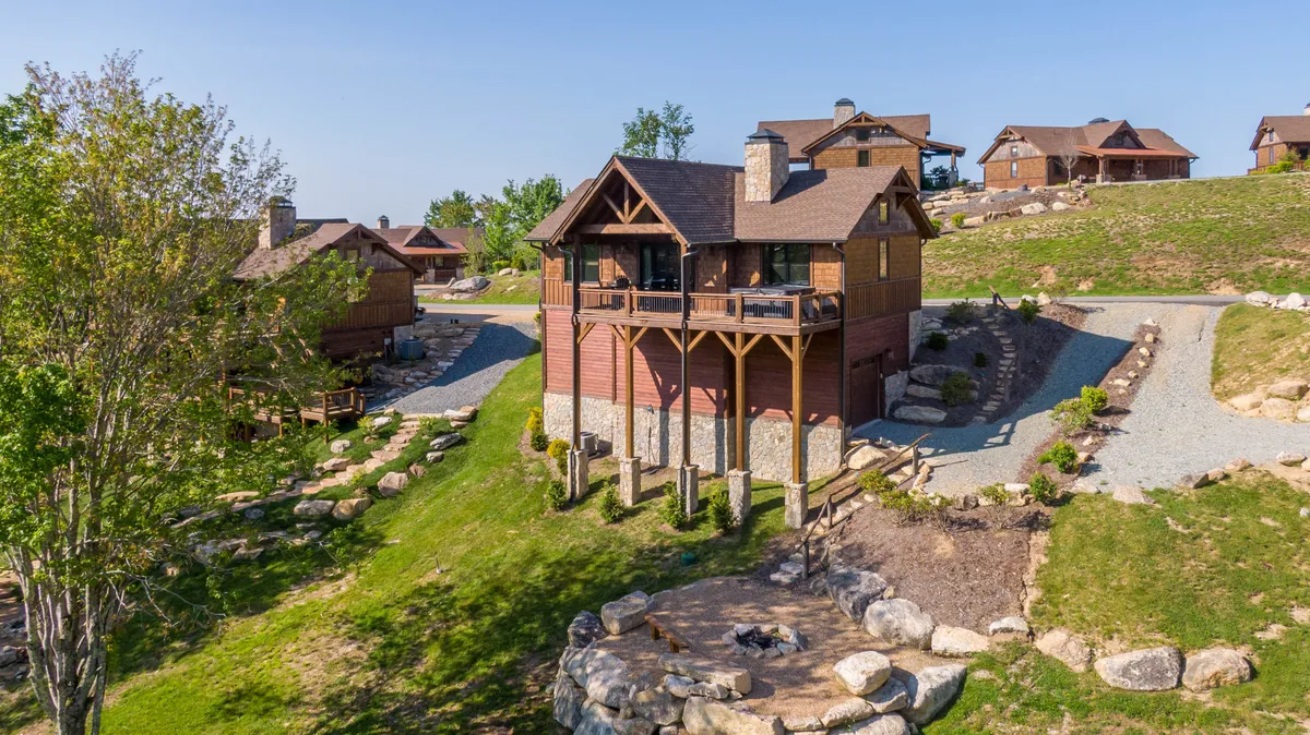 The image captures the firepit area outside the cabin, surrounded by a landscaped garden and stone pathways. The tranquil setting is ideal for evenings spent by the fire, sharing stories or roasting marshmallows with loved ones.