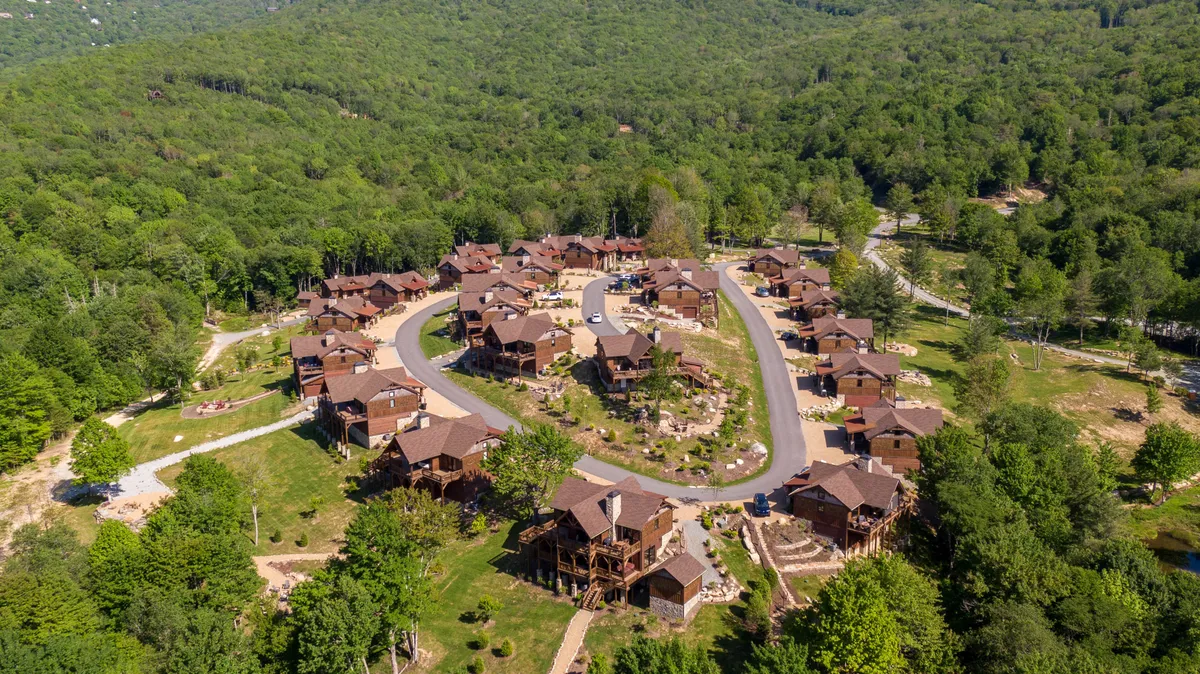 This image shows a peaceful cluster of houses nestled among trees, with a gently curving road and the welcoming ambiance of a mountain neighborhood. The neighborhood is surrounded by natural beauty, inviting outdoor walks and exploration.